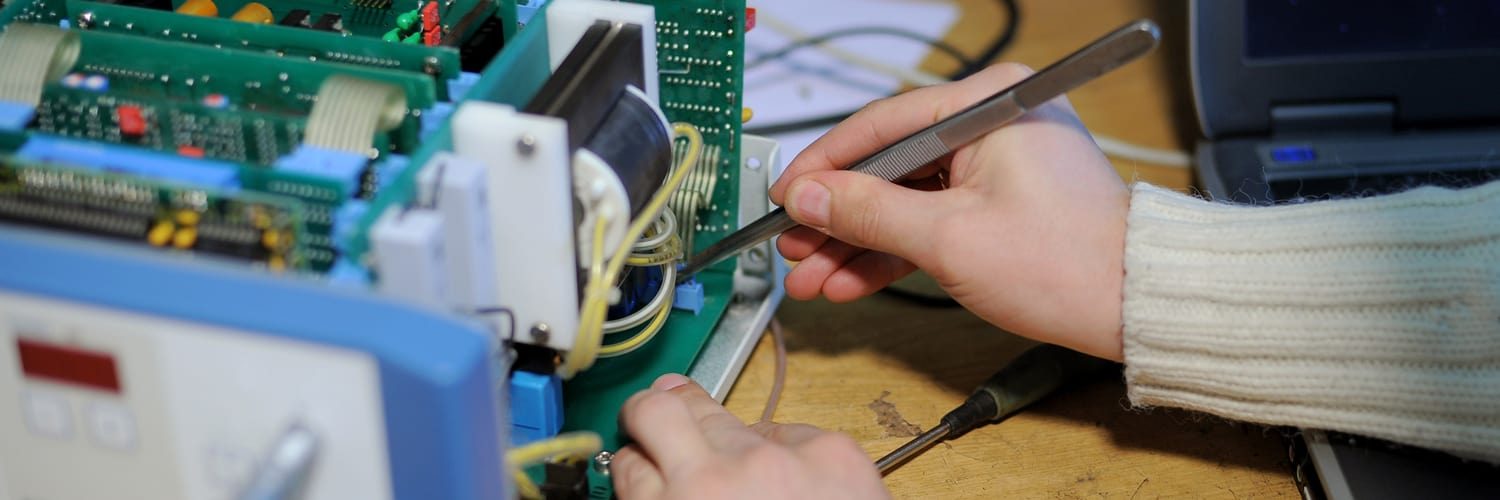 Technician repairing a circuit board with tweezers