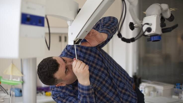 Technician performing maintenance on medical equipment overhead